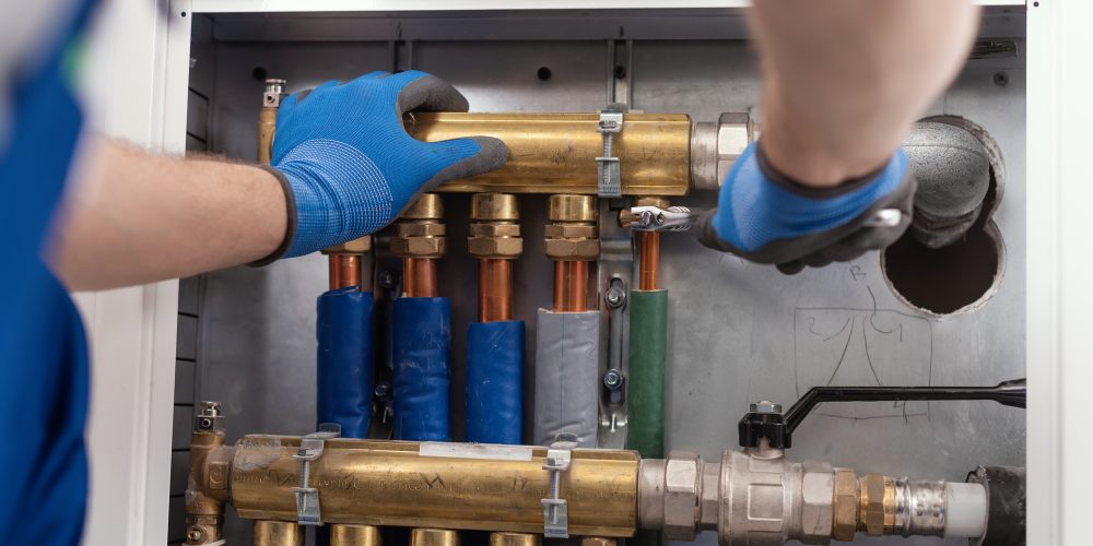 professional-plumber-installing-plumbing-manifolds-EM447BZ